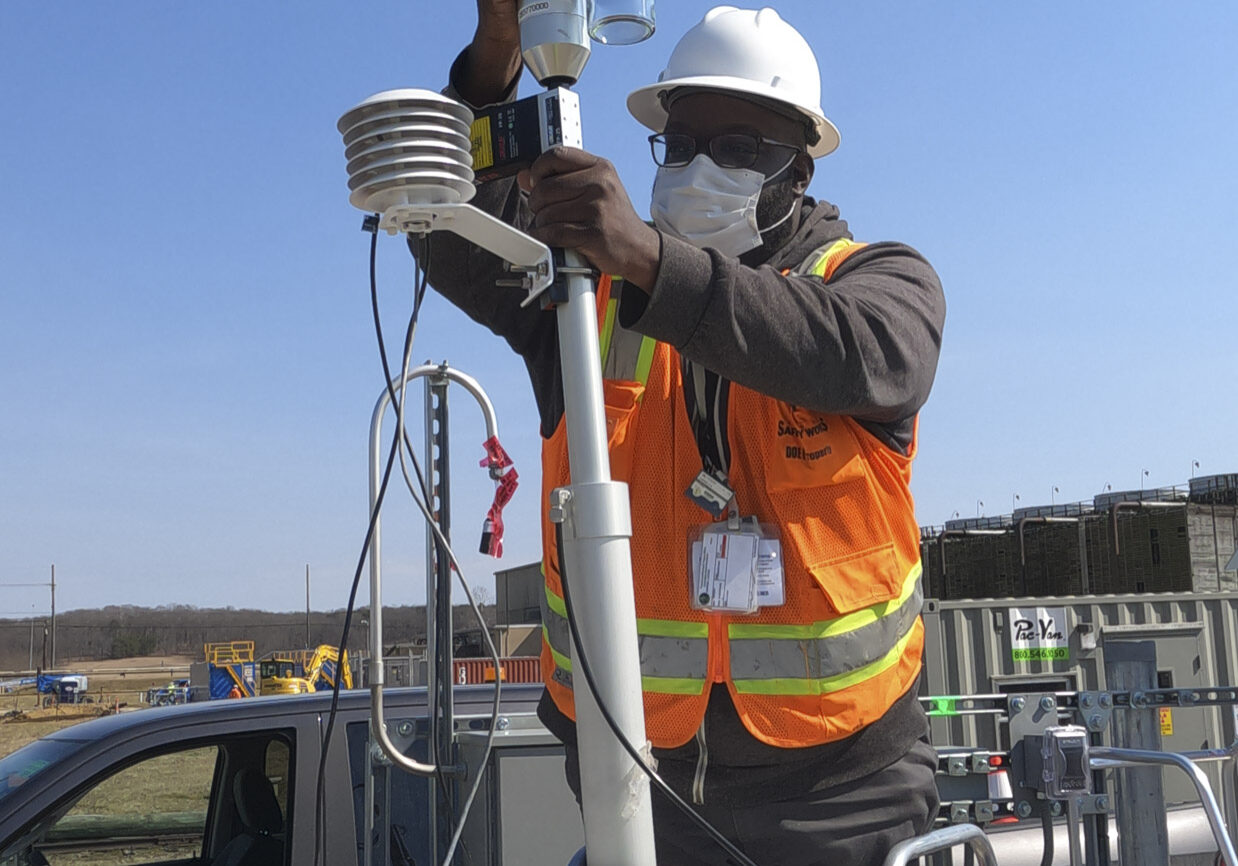 A worker adjusts an on-site air monitor.